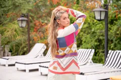 Sweater de punto con diseño geométrico multicolor y cuello redondo. El borde del cuello, puños y ruedo es de color salmón fluorescente.