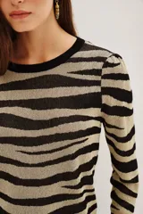 Sweater de tejido de punto con cuello redondo y manga larga, presentando un estampado de rayas negras y beige metalizado con efecto cebra.
