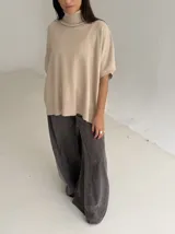 Poncho de tejido de punto color marrón chocolate, con cuello alto tipo polera y mangas cortas amplias. Presenta un diseño holgado con terminaciones acanaladas en el ruedo.