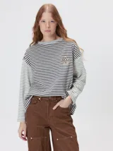 Remera de manga larga con diseño a rayas horizontales en tonos celestes y blancos en el cuerpo, y mangas a rayas azul marino y blancas. Presenta cuello redondo en color azul marino, logo bordado en el pecho y calce holgado.