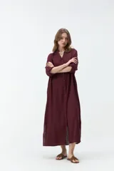 Vestido largo color bordó, tipo camisero, con cuello mao, escote en V y cierre frontal con botones. Mangas largas con vuelta y diseño holgado.