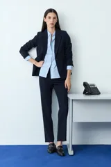 Pantalón de corte recto y estilo sastrero, confeccionado en tela de color negro, con cierre frontal y bolsillos laterales.