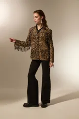 Blazer de poliéster con estampado animal print de leopardo, diseño holgado, cuello solapa, cierre frontal con botones y flecos decorativos en el pecho y la espalda. Incluye bolsillos frontales.