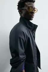 Parka de corte relajado confeccionada en tejido de algodón con efecto lavado. Presenta cuello subido, manga larga con puños abotonados, bolsillos frontales de plastrón con solapa y cintura ajustable mediante cordón interior. El cierre frontal es de cremallera oculta por una solapa con botones a presión.