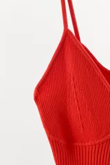 Body confeccionado en mezcla de viscosa y poliamida, color rojo. Presenta un diseño de punto rib con escote en pico, tirantes finos y cierre inferior con botones a presión.