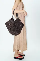 Bolso formato shopper de color marrón con cuerpo trenzado y diseño geométrico. Cuenta con doble asa de hombro en combinación de materiales y compartimento interior extraíble con cremallera.