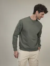 Sweater verde militar de cuello redondo y manga larga con detalle de bolsillo con solapa en la manga izquierda.