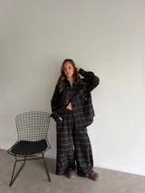 Pantalón de corte recto y holgado, confeccionado en tela de viyela con estampado de cuadros en tonos negro, gris y blanco. Presenta cintura elástica para mayor comodidad.