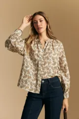 Camisa de manga larga con cuello mao y estampado paisley en tonos beige, marrón y azul sobre fondo claro. Presenta un calce holgado y puños ajustados.