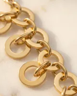 Set de joyería compuesto por un collar de cadena con eslabones circulares entrelazados y aros colgantes a juego con diseño de doble círculo, ambos con acabado en tono dorado.