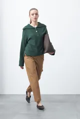 Sweater de tejido de punto color azul marino, con cuello polo amplio y cierre frontal con tres botones metálicos. Presenta mangas largas levemente acampanadas y un diseño de silueta relajada con aberturas laterales en el ruedo.