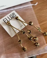 Caravanas largas de bronce con diseño de varillas onduladas y apliques de piedras oscuras con detalles en dorado. Hechas a mano.