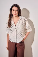 Blusa de lino y viscosa color blanco con estampado de lunares marrones, de manga corta y cuello camisero con cierre frontal de botones.