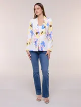 Blazer de silueta semientallada confeccionado en tela sastrera de color blanco con estampado floral en tonos amarillos, celestes, rosados y azules. Presenta solapa de muesca clásica, acceso frontal mediante un botón a tono, bolsillos simulados con solapa y mangas largas de corte clásico.