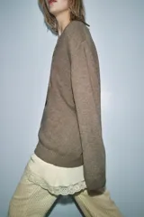 Jersey de lana color marrón con escote en V y manga larga. Incluye un detalle de vestido interior de color crema con encaje en el bajo.