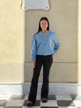 Camisa de jean celeste con cuello redondo, cierre frontal con botones y mangas largas abullonadas con puños ajustados.