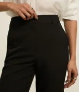 Pantalón de vestir gris oscuro, de corte recto, con bolsillos laterales y traseros. Se ajusta a la cintura con cinturón de cuero marrón.