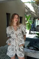 Short de tiro medio con pierna holgada, color blanco con estampado de motivos florales en tonos tierra. Presenta bolsillos delanteros y un cordón de ajuste en la cintura.