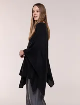 Poncho de calce holgado color marrón, confeccionado en tejido fino de punto suave, con cuello redondo y diseño de caídas laterales amplias de ruedo asimétrico.
