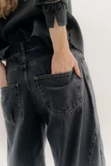 Pantalón de jean color beige, de tiro medio, corte amplio y ruedo acampanado.