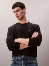 Remera de manga larga negra de corte holgado, con cuello redondo y el logo monograma de Calvin Klein bordado en blanco en el pecho.