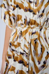 Vestido largo con estampado animal print en tonos camel, blanco y negro. Tiene escote en V, mangas cortas tipo murciélago y tajo frontal. Incluye cinturón ancho de cuero color camel.