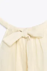 Top de gasa color menta con cuello halter y lazada posterior. Presenta detalles de bordados calados a tono y un bajo con terminación en volante.