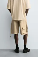 Bermuda de corte relajado en denim de algodón color beige, estilo cargo, con cinco bolsillos y bolsillos plastrón con solapa en las perneras.