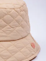 Gorro tipo bucket color beige con diseño acolchado de rombos y pequeño logo circular en el lateral.