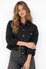 Campera de jean color negro con cierre frontal de botones metálicos, cuello clásico, bolsillos frontales con solapa y mangas largas.