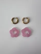 Aros de acero quirúrgico dorados con argollas pequeñas y dijes colgantes en forma de flor color celeste.