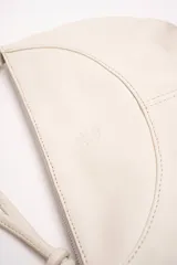 Cartera bandolera de cuero marrón con forma relajada, diseño de costuras curvas y detalles de nudos hechos a mano en las asas.