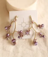 Aros colgantes con forma de rama color bronce, decorados con cuentas facetadas de color lila y cristal. Cierre de tuerca a presión.