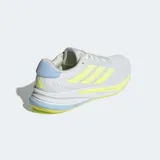 Championes de running Adidas Supernova Ease, color blanco con detalles en amarillo flúor y celeste. Presentan tres franjas laterales en amarillo flúor y mediasuela con tecnología Dreamstrike+.