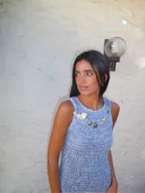 Vestido largo de crochet con diseño de red, en tonos rojizos y blancos. Presenta un corte sin mangas y una falda con volados en la parte inferior.
