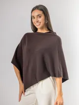 Poncho de corte holgado y diseño minimalista, confeccionado en tejido liviano de color beige, con cuello redondo y caída fluida.