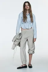 Pantalón bombacho de tiro medio con cintura elástica, confeccionado en tejido de nylon con estampado de cuadros pequeños en blanco y negro. El bajo es elástico con abertura y botón a presión.