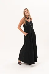 Vestido largo de denim fino y liviano color negro, de breteles finos, escote delicado, silueta entallada arriba y falda amplia con bolsillos laterales.