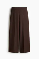 Pantalón de punto color marrón, de tiro alto con cintura elástica y diseño de piernas amplias con pliegues frontales cosidos.