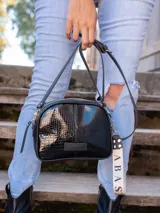 Bandolera pequeña de cuero negro con textura tipo cocodrilo, correa larga ajustable y llavero con el logo de la marca.