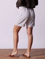 Short blanco con rayas verticales grises, de lino y rayón. Tiene pretina ancha elastizada con lazo de ajuste y bolsillos delanteros.