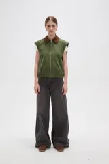 Chaleco de algodón color verde oliva, con cierre frontal y cuello de pana en color marrón. Presenta un diseño holgado con elástico en la cintura.