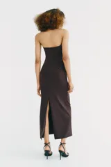 Vestido midi de escote recto con cuello halter y aplicación metálica tipo choker. Presenta frunces laterales en el delantero, abertura en la espalda y cierre con cremallera oculta.