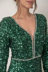 Vestido corto verde esmeralda de paillettes con escote en V y mangas largas. Presenta detalle de strass en el escote y la cintura, y corte recto.