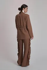 Blazer negro con solapas de muesca, corte holgado, cierre frontal con lazo y detalle de volados en los bolsillos.