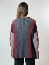 Sweater de punto grueso con cuello alto, diseño de bloques de color en azul marino, azul claro, fucsia y bordó. Presenta mangas largas y un corte holgado.
