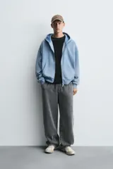 Sudadera con capucha y cierre de cremallera, de corte relajado (relaxed fit), confeccionada en algodón con interior afelpado. Presenta bolsillos frontales tipo canguro y acabados en rib. El tejido tiene un efecto lavado que le da un color negro desgastado.