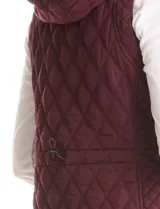 Chaleco de abrigo capitoneado color bordó, con capucha integrada, cierre frontal y bolsillos laterales con botón a presión. Presenta un diseño entallado con forro interior suave.