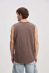 Musculosa oversize de algodón color marrón con efecto lavado desgastado, de corte amplio y sin mangas. Cuenta con una estampa frontal en relieve y diseño urbano de la marca Mistral.