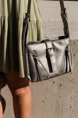 Bandolera plateada con correa larga y varios cierres con borlas.